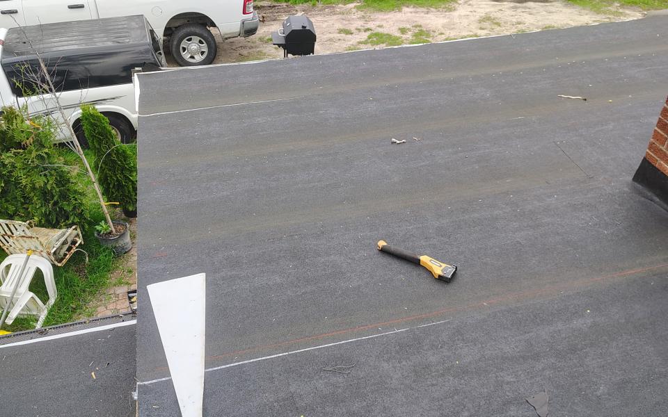 Contractor inspecting a residential asphalt roof during the fall season