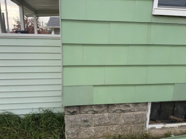 Repaired siding on a green sided home by Michigan Exterior Pros.