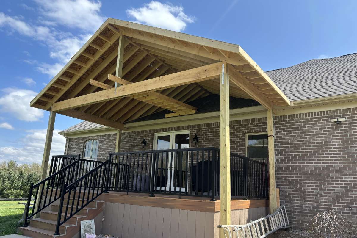 Gable roof porch addition framed over a composite deck on a brick home by Michigan Exterior Pros.