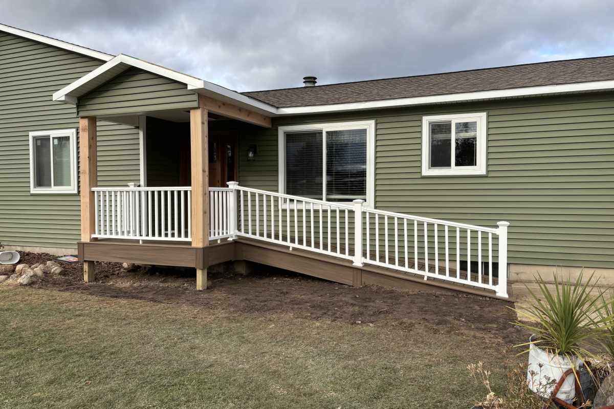 Covered front porch with cedar posts, composite ramp, and white railings built by Michigan Exterior Pros.