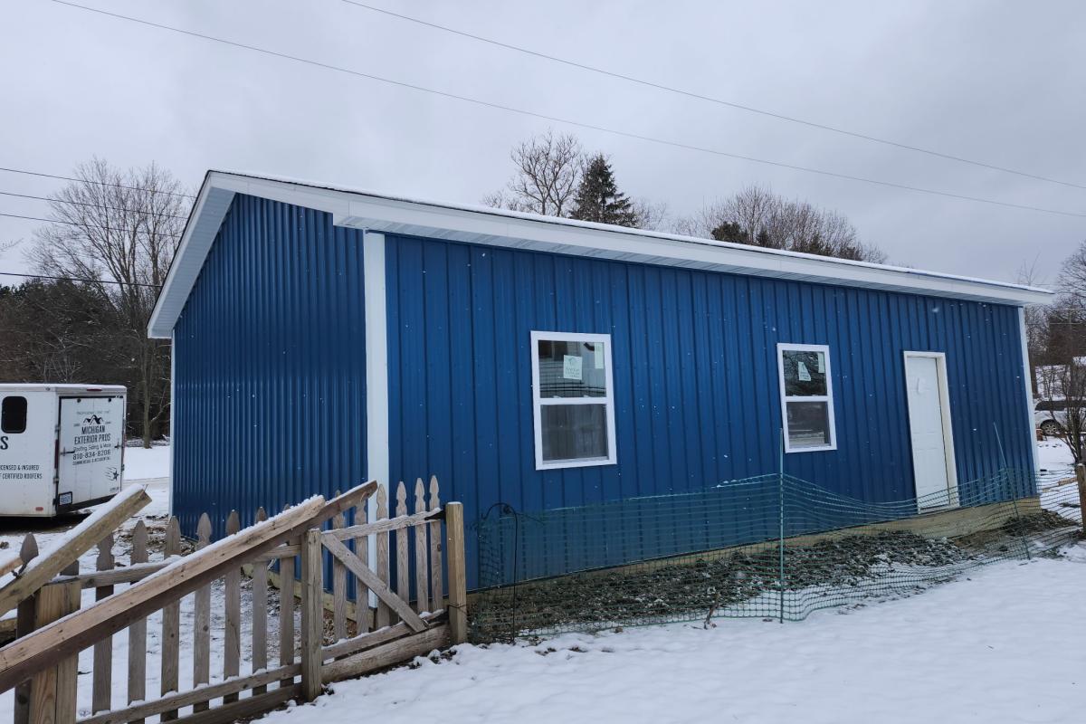 Custom blue colored pole barn with white trim built by Michigan Exterior Pros.